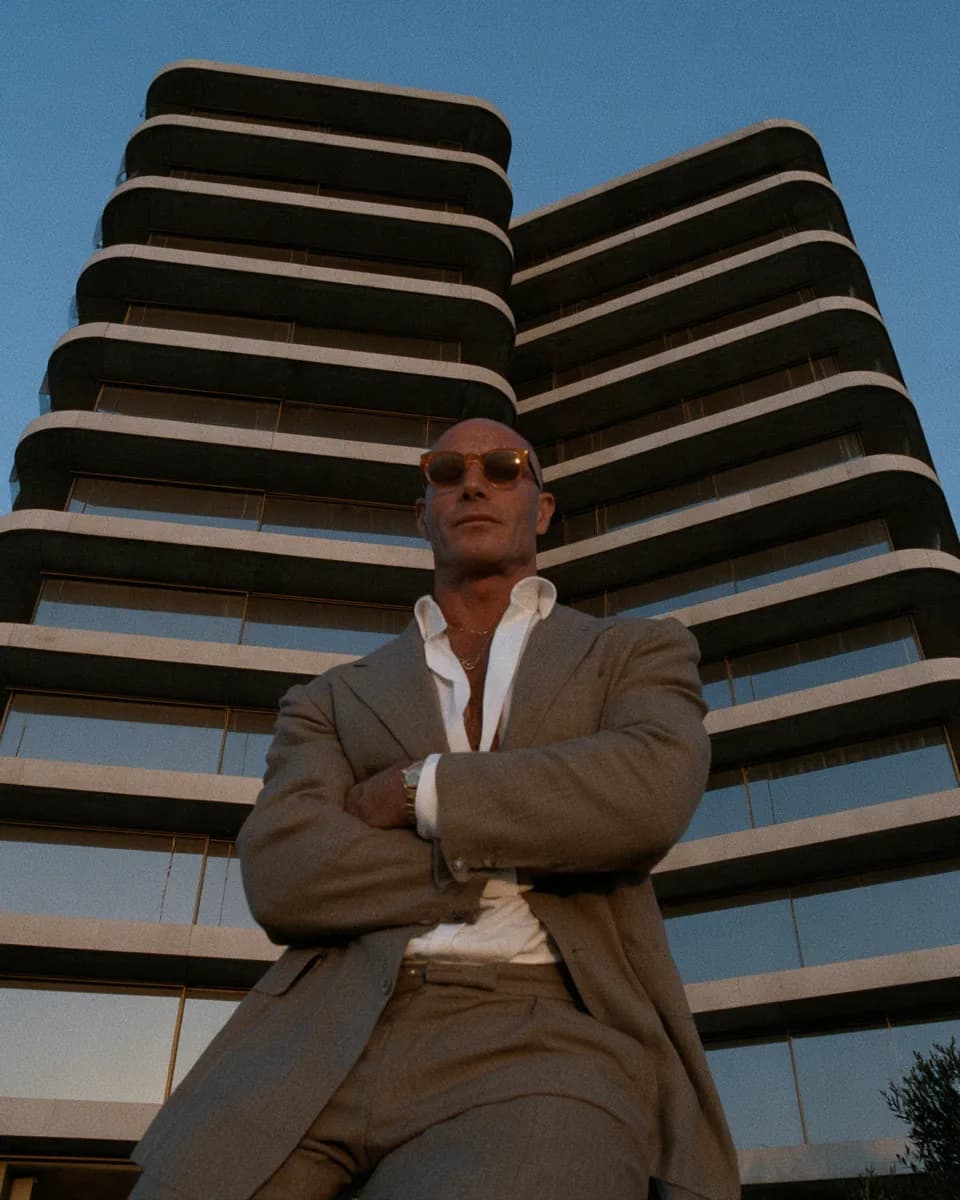A developer standing in front of an apartment tower